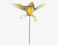 Dekorativ havelåge med et fantasifuldt insektdesign, der har en klar gul krop, store sorte og hvide øjne samt røde detaljer på hovedet. Insektet har gennemsigtige grønne vinger med gule spidser og udstrakte gule ben. Figuren er monteret på en lang, slank metalstang, så den nemt kan placeres i jorden.