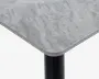 Nærbillede af et bordhjørne med en glat, rektangulær bordplade med afrundede kanter. Bordpladen har et lysegråt marmorlignende mønster og en let skrå kant. Bordbenet er cylindrisk og sort, hvilket giver en moderne kontrast til den lyse overflade.