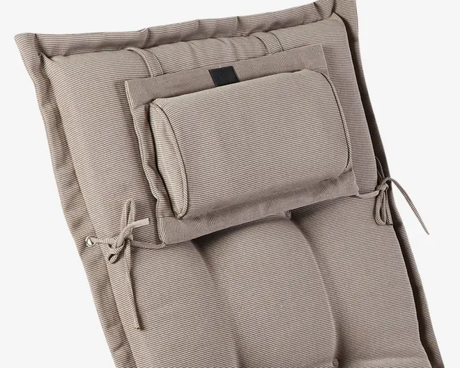 Nærbillede af en polstret hynde med et diskret stribet mønster i beige og lysebrune nuancer. Hynden har en indbygget, justerbar nakkepude, der er fastgjort med stofstropper og bindebånd i siderne til fastgørelse. Overfladen ser blød og fyldig ud med synlige syninger og polstrede sektioner for ekstra komfort og støtte.