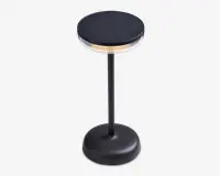 En moderne, sort bordlampe med rund fod og en slank, lodret stang. Lampen har en cirkulær top med solpaneloverflade, en gennemsigtig ring under toppen for blødt lys og en touch-tænd/sluk-knap på foden. Designet er stilrent og minimalistisk, velegnet til moderne indretning.