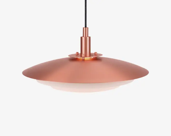 En moderne pendellampe med en bred, flad og cirkulær skærm i metallisk kobberfinish. Skærmen har en glat overflade og skråner let nedad, med en hvid diffuser i bunden for blød og jævn lysfordeling. Lampen hænger i en sort ledning og har et stilrent, minimalistisk design, der passer til moderne indretning.