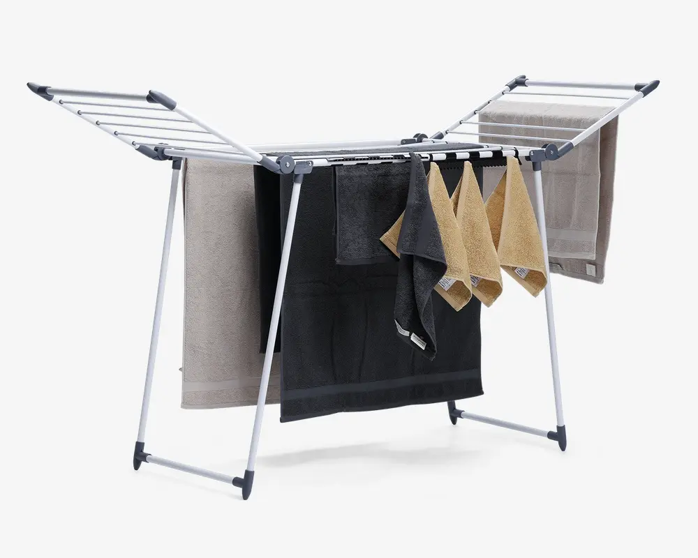 Sammenklappeligt tørrestativ med robust metalramme og flere vandrette stænger til ophængning af tøj. Stativet har to udtrækkelige vinger på hver side for ekstra tørreplads og er vist med håndklæder i forskellige farver og størrelser. Foden har plastikbeskyttelse for stabilitet og for at undgå ridser på gulvet.