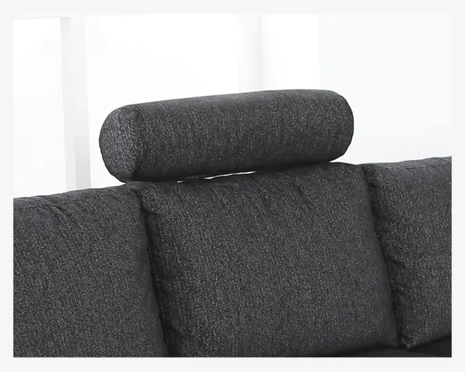 Nærbillede af en mørkegrå, cylindrisk nakkestøtte, der er fastgjort øverst på sofaens ryglæn. Nakkestøtten er betrukket med et tekstureret stof, der matcher sofaens puder, og giver ekstra støtte til nakke og hoved. Sofaens puder er bløde og let afrundede, hvilket indikerer en komfortabel siddeoplevelse.
