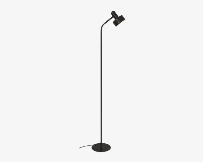 Høj, slank gulvlampe med mat sort finish, rund fod for stabilitet og justerbart, vinklet lampehoved til at rette lyset. Lampen har et minimalistisk design og en synlig ledning, der går ud fra bunden.