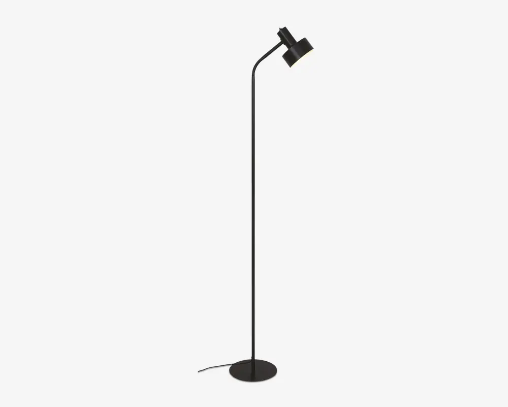 Høj, slank gulvlampe med mat sort finish, rund fod for stabilitet og justerbart, vinklet lampehoved til at rette lyset. Lampen har et minimalistisk design og en synlig ledning, der går ud fra bunden.