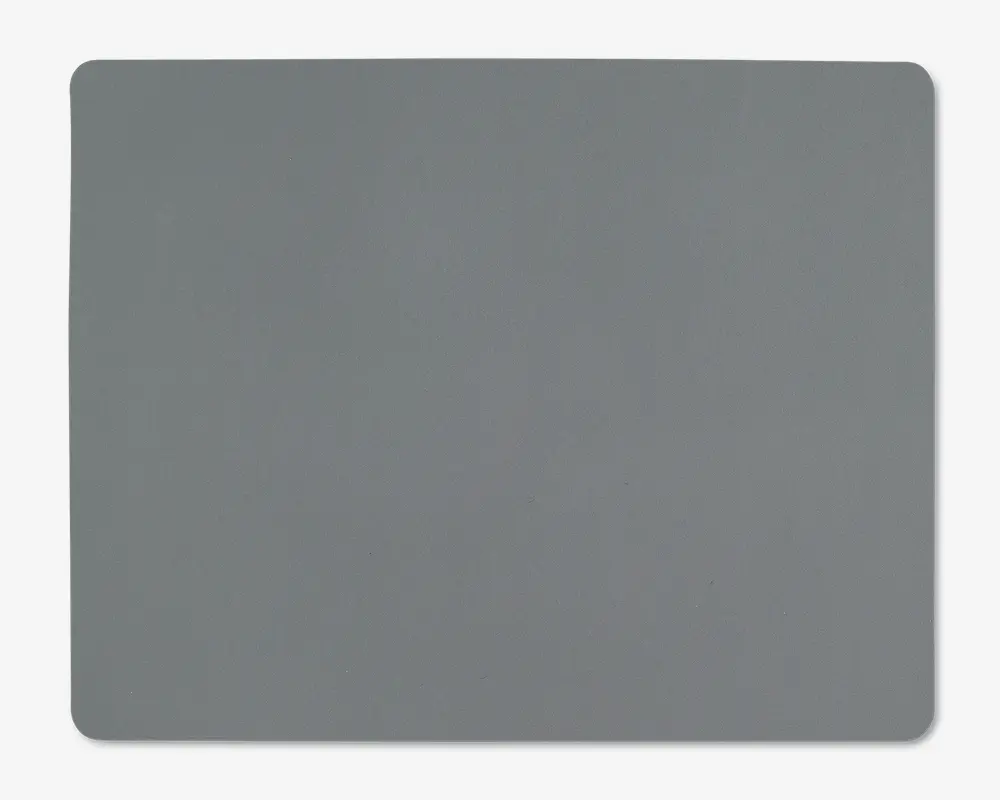 Et rektangulært underlag med afrundede hjørner og en glat, ensfarvet grå overflade. Kanterne er let hævede, og materialet ser blødt og fleksibelt ud, velegnet til brug på et skrivebord eller bord.
