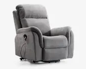 Blød, grå polstret lænestol med tykt polstret ryglæn, sæde og armlæn for ekstra komfort. Har en sidelomme til opbevaring af fjernbetjening samt en tilsluttet ledning, hvilket indikerer elektrisk recliner- eller massagefunktion. Stolen har et moderne, indbydende design med blødt stof og let buede former.