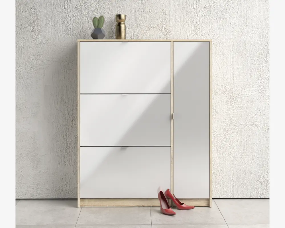 Moderne opbevaringsskab med lyst træramme og blanke hvide fronter. Skabet har tre vandrette rum til venstre og et højt, lodret rum til højre, alle med diskrete greb. Øverst står en lille potteplante, en geometrisk vase og en guldfarvet dekorationsgenstand. Et par røde højhælede sko står på gulvet foran skabet. Baggrunden er en hvid, struktureret væg og lyse gulvfliser.