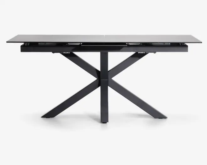 Rektangulært bord med en glat, lysefarvet bordplade og en robust, sort metalbase. Basen har et moderne krydsbenet design, der giver ekstra stabilitet og et stilrent udtryk. Bordpladen ser ud til at være lavet af et holdbart materiale, muligvis glas eller keramik, og bordet har et slankt, minimalistisk look, der passer til moderne indretning.