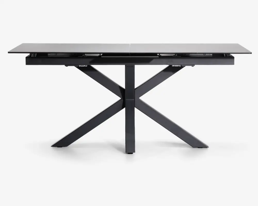 Rektangulært bord med en glat, lysefarvet bordplade og en robust, sort metalbase. Basen har et moderne krydsbenet design, der giver ekstra stabilitet og et stilrent udtryk. Bordpladen ser ud til at være lavet af et holdbart materiale, muligvis glas eller keramik, og bordet har et slankt, minimalistisk look, der passer til moderne indretning.