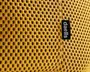 Nærbillede af et sennepsgult stof med en åndbar, bikubeformet mesh-struktur. Stoffet har et lille sort mærke med teksten 'daells' i hvid, som er syet ind i en syning.