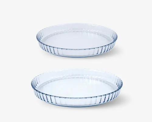 Sæt med to runde, klare glasskåle med riflede sider og flad bund. Skålene er lavt dybe og har en glat kant, velegnet til bagning eller servering. Det gennemsigtige glas gør det nemt at se indholdet, og det riflede design giver et dekorativt udtryk.