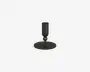 Et lysestage i mat sort metal med en cylindrisk holder til lyset, understøttet af en lille kugleformet detalje over en slank stang. Basen er bred og flad, hvilket giver stabilitet og et moderne, minimalistisk udtryk.