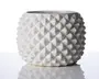 En rund, hvid keramisk beholder med en markant geometrisk tekstur, der består af hævede diamantformede knopper over hele ydersiden. Overfladen er blank, hvilket giver et moderne og stilfuldt udtryk. Åbningen foroven er bred, og det samlede design er både dekorativt og funktionelt.