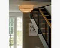 Loftmonteret lampe med et moderne, lagdelt design bestående af tre koncentriske tromleformede lampeskærme i neutral beige stof. Lampen udsender et varmt, diffust lys, der skaber en hyggelig stemning. Stoffets tekstur giver et blødt og elegant udtryk, der passer til moderne indretning.
