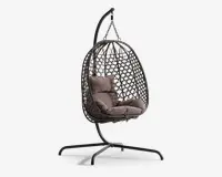Hængende æggeformet stol med flettet rattanramme, ophængt fra et robust sort metalstativ. Stolen har bløde, taupefarvede sæde- og ryghynder for ekstra komfort. Den åbne gitterstruktur i rammen giver god luftcirkulation og et moderne udtryk. Basen er bred og stabil, hvilket sikrer sikker placering både indendørs og udendørs.
