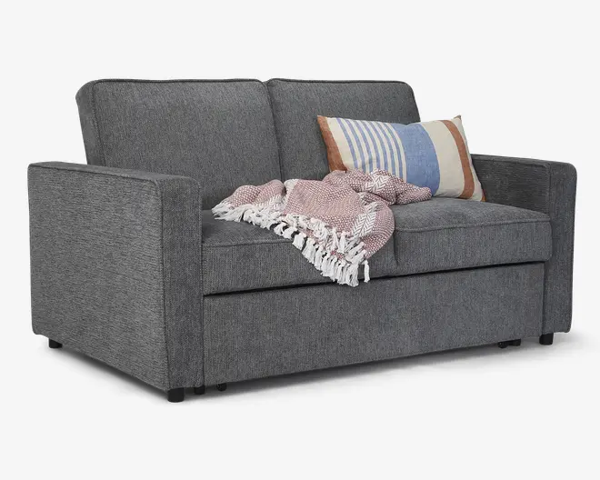 En moderne 2-personers sofa betrukket med mørkegråt stof, med rene, lige linjer og firkantede armlæn. Sædehynderne er faste, og ryghynderne er let skrånende for komfort. Over den ene side ligger et tekstureret, lyserødt og hvidt plaid med frynser, og der er en dekorativ pude med stribet mønster i blå, hvid og tan nuancer, som tilføjer farve og hygge.