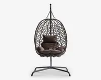 Hængende æggeformet stol med flettet rattanramme, understøttet af et robust metalstativ. Stolen har bløde, mørkebrune puder, herunder en siddepude, to sidepuder og en rygpude for ekstra komfort. Den åbne fletning giver god luftcirkulation og et moderne udseende, hvilket gør den velegnet til både indendørs og udendørs brug.