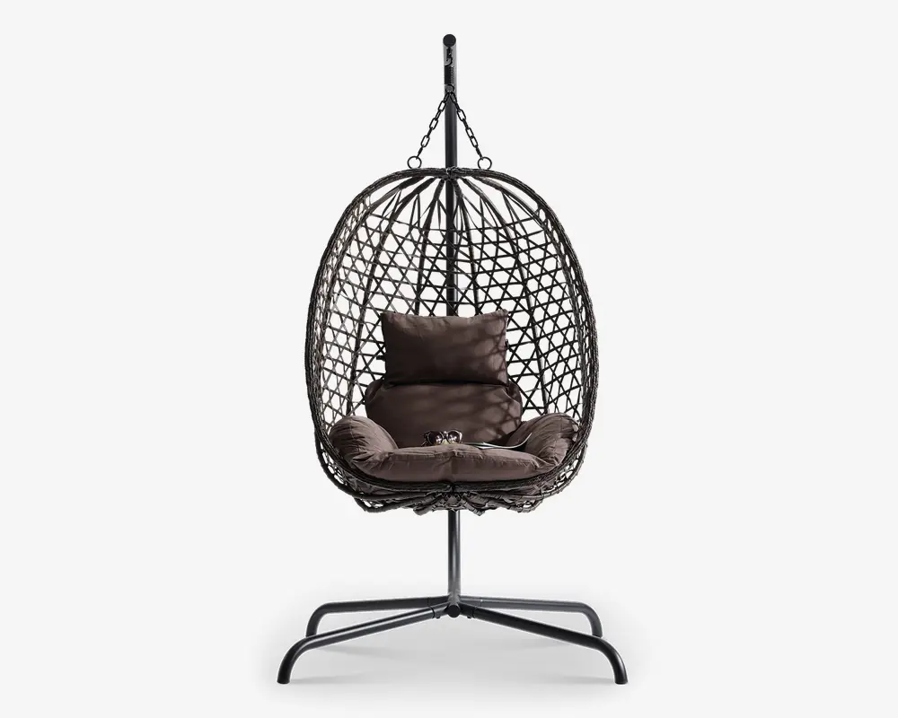 Hængende æggeformet stol med flettet rattanramme, understøttet af et robust metalstativ. Stolen har bløde, mørkebrune puder, herunder en siddepude, to sidepuder og en rygpude for ekstra komfort. Den åbne fletning giver god luftcirkulation og et moderne udseende, hvilket gør den velegnet til både indendørs og udendørs brug.