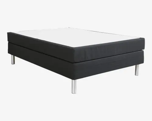 Rektangulær sengebund med minimalistisk design, sort stofbetrukket ramme og hvid topflade. Sengen står på seks cylindriske ben i metal med blank kromfinish, hvilket giver solid støtte og et moderne udtryk. Kanterne er lige og rene, hvilket giver et tidssvarende look.