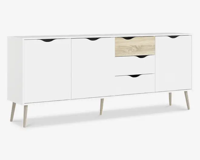 Et moderne skænk med et minimalistisk design, mat hvid finish og detaljer i lyst træ. Den står på fire skrå træben og har tre skuffer i midten (den øverste skuffe har en lys træfinish, de to andre er hvide) samt tre skabslåger med udskårne greb for nem åbning. Udtrykket er stilrent og nutidigt, velegnet til mange forskellige indretninger.