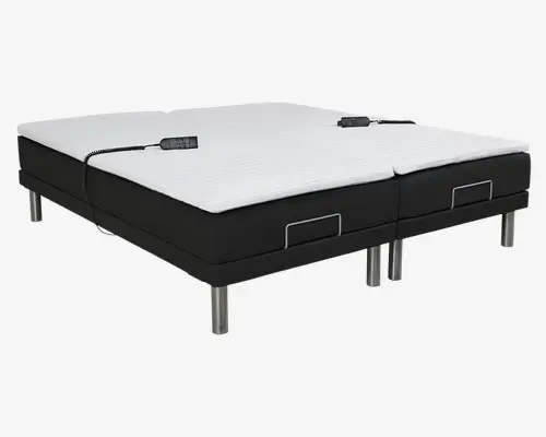 Justerbar sengebund med to separate sektioner, hver med en hvid, quiltet madras-topper og sort polstret bund. Begge sider har individuelle fjernbetjeninger forbundet med ledninger, hvilket muliggør personlig justering. Sengen står på seks solide, cylindriske metalben, og hver sektion har en metalstang ved fodenden for at holde madrassen på plads.