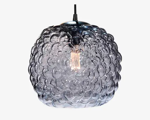 Kugleformet loftslampe med en klar, struktureret glasskærm, der har et hævet boblemønster. Glasset giver et dekorativt, næsten blomsterlignende udtryk, og pæren er synlig indeni, hvilket tilføjer et moderne og kunstnerisk præg. Lampen hænger i en sort ledning.