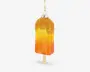 En dekorativ ornament formet som en ispind, med en farveovergang fra orange til gul og et glitrende finish. Toppen af ornamentet er dækket af gyldne perler, der ligner krymmel, og det hænger i en gylden snor. Ornamentet har en realistisk træpind i bunden.