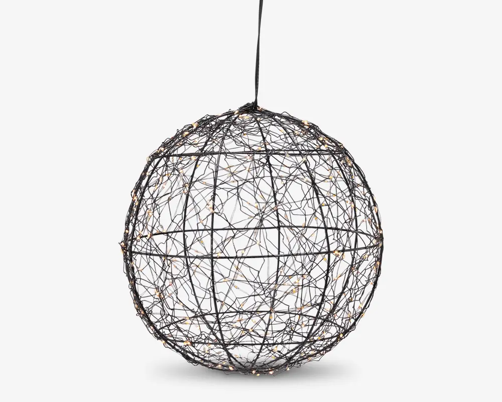 En kugleformet loftslampe lavet af sammenflettede metaltråde, der danner en globusform. Trådene er arrangeret i et krydsmønster, hvilket giver et åbent og let udtryk. Små LED-lys er fordelt over hele strukturen og giver en glitrende effekt, når lampen er tændt. Lampen hænger i en enkelt ledning fra toppen.
