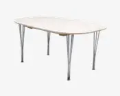 Rektangulært bord med afrundede hjørner, glat lys træbordplade og fire slanke, skråtstillede ben i krom. Designet er minimalistisk og moderne med en tynd bordplade og synlige metalbeslag under bordet.