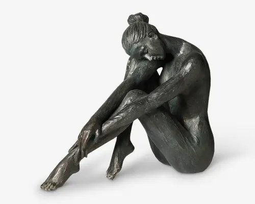 Bronzeskulptur af en siddende figur med et eftertænksomt udtryk, armene er viklet omkring bøjede knæ, og hovedet hviler blidt på underarmene. Overfladen har en tekstureret, håndbearbejdet finish, der fremhæver anatomiske detaljer og muskulatur. Figurens hår er sat op i en løs knold, og den samlede positur udstråler eftertænksomhed og ro.