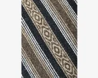 Nærbillede af et vævet tekstil med skiftevis diagonale striber i brune, beige, sorte og hvide nuancer. Mønstret indeholder teksturerede diamantformer i nogle striber og fine zigzaglignende linjer i andre, hvilket giver stoffet et rustikt og traditionelt udtryk.