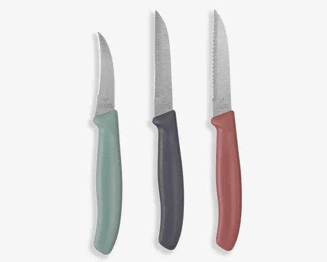 Tre smalle knive med rustfri stålblade og ergonomiske plasthåndtag i mintgrøn, mørkegrå og rosa; det ene blad er glat og let buet, mens de to andre har savtakket æg.