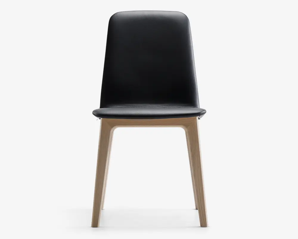 Stol med glat, sort, høj ryg og sæde, der har et minimalistisk design. Benene er lavet af lyst træ og har en let vinklet form, hvilket giver et moderne og enkelt udtryk. Sædet og ryglænet ser ud til at være polstret med et læderlignende materiale.