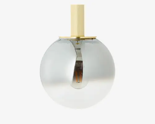 En moderne pendellampe med en kugleformet glasskærm, der har en diskret farveovergang fra klar i bunden til røgfarvet i toppen. Lampen har en messing- eller guldfarvet metalstang og top, hvilket giver et stilrent og elegant udtryk. Pæren er synlig inde i lampen, hvilket understreger det moderne design.