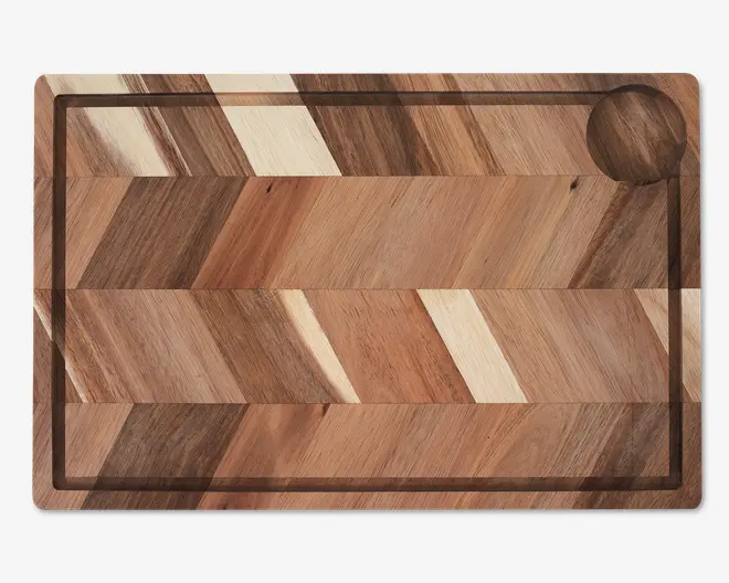 Rektangulær plade lavet af flere træstrimler i forskellige nuancer, arrangeret i et sildebensmønster. Har en rille langs den indvendige kant til opsamling af væske og en cirkulær fordybning i det ene hjørne, sandsynligvis til småting eller ingredienser. Overfladen er glat, og træets årer er tydelige over hele pladen.