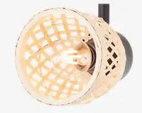 Nærbillede af en lampe med en rund, åben fletskærm i naturfarvet rattan eller flet. Skærmen har et gittermønster, der lader lyset skinne igennem og skaber en varm og hyggelig stemning. En klar pære er synlig indeni, og lampen er monteret på en sort base. Designet kombinerer et rustikt og moderne udtryk.