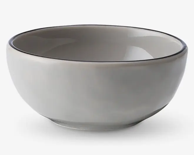 En rund, mellemstor skål af keramik med en glat, blank lysegrå yderside og inderside. Skålen har en let tyk kant med en diskret, mørkere kantdetalje. Det enkle og minimalistiske design gør den velegnet til mange forskellige borddækninger.