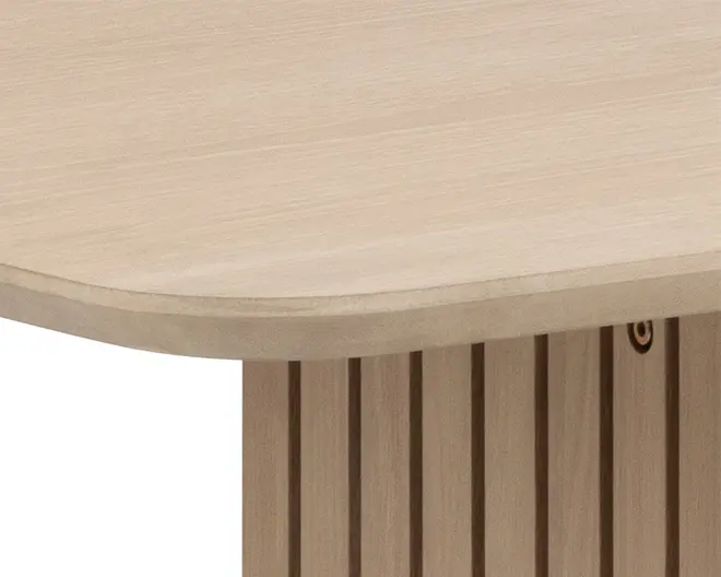 Nærbillede af en lys træoverflade med afrundet kant og en lodret støtte med jævnt fordelte, smalle riller, der giver et tekstureret udtryk. Overfladen er glat og mat, hvilket fremhæver træets naturlige årer.