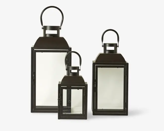 Sæt med tre rektangulære lanterner i forskellige størrelser, hver med sort metalramme og klare glasruder på alle sider. Lanternerne har fladt topstykke og rund hank, der gør dem nemme at bære eller hænge op. Designet er enkelt og moderne, velegnet til både indendørs og udendørs brug.