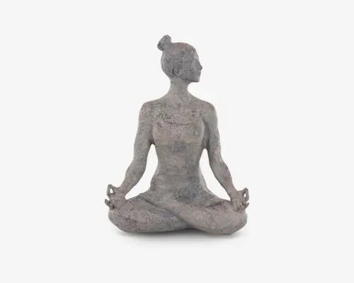Dekorativ skulptur med stenlignende overflade, der forestiller en person siddende i skrædderstilling i en meditativ positur med hænderne hvilende på knæene og fingrene formet i en mudra. Overfladen har en tekstureret, marmoreret effekt, og figurens hår er sat op i en knold. Designet udstråler ro og harmoni og egner sig til både indendørs og udendørs dekoration.
