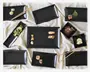 Et sæt elegante, matte sorte rektangulære og firkantede tallerkener arrangeret på et lyst stof. Tallerkenerne har let hævede kanter og et moderne, minimalistisk design. Nogle tallerkener viser sushi, limebåde og pynt, hvilket fremhæver deres anvendelse til servering af forretter eller små retter. Træspisepinde er også til stede, hvilket understreger sættets egnethed til asiatisk mad.