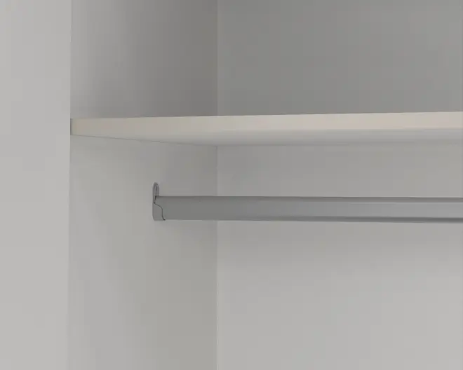 Nærbillede af et klædeskab indvendigt med en solid metal bøjlestang monteret mellem to vægge og en hvid hylde placeret ovenover til ekstra opbevaring. Overfladerne er glatte, og designet er minimalistisk, hvilket giver god plads til ophængning af tøj og opbevaring af ting på hylden.