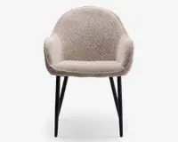 En moderne lænestol med rund ryg og integrerede armlæn, polstret med et blødt, tekstureret beige stof. Sædet er tykt polstret for ekstra komfort. Stolen står på fire slanke, let skråtstillede sorte metalben, hvilket giver et elegant og moderne udtryk.