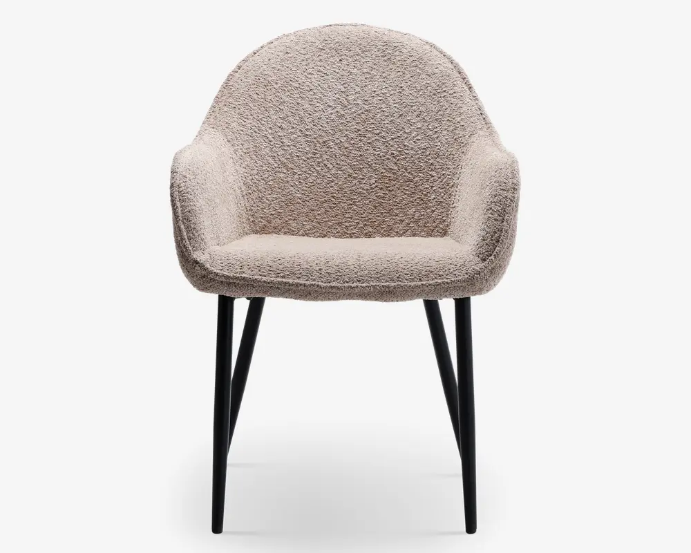 En moderne lænestol med rund ryg og integrerede armlæn, polstret med et blødt, tekstureret beige stof. Sædet er tykt polstret for ekstra komfort. Stolen står på fire slanke, let skråtstillede sorte metalben, hvilket giver et elegant og moderne udtryk.