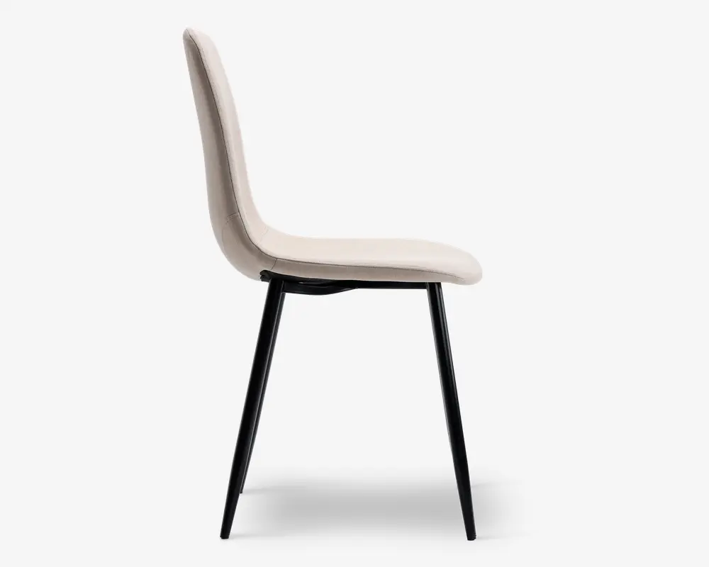 Sidebillede af en moderne stol med let buet, polstret ryg og sæde betrukket med et lyst beige stof. Stolen har slanke, skråtstillede sorte metalben, der giver et minimalistisk og moderne udtryk. Sæde og ryg er sømløst forbundet og giver ergonomisk støtte.