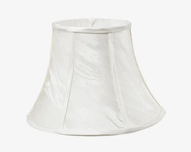 En klassisk klokkeformet lampeskærm lavet af hvidt stof med et diskret tekstureret mønster. Skærmen har lodrette stofpaneler adskilt af smalle syninger og en let udvidet bundkant med forstærket kant både foroven og forneden for ekstra stabilitet.