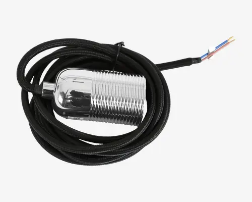 En cylindrisk, metalgenstand med blank kromfinish og rillet overflade for bedre greb. Den har et langt, sort flettet kabel fastgjort i den ene ende, og i den anden ende er der tre blotlagte farvede ledninger (blå, brun og gul/grøn) til elektrisk tilslutning. Komponentens design virker robust og egnet til nem montering, sandsynligvis til brug i industrielle eller tekniske miljøer.