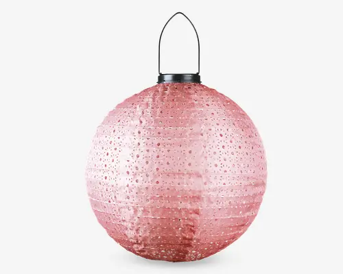 Rund lanterne i en blød rosa farve med et mønster af små, cirkulære huller over hele overfladen, som lader lyset skinne igennem. Lanternen har et sort metalhåndtag øverst, så den er nem at hænge op eller bære. Materialet virker let, sandsynligvis papir eller tyndt metal, hvilket giver lanternen et elegant og dekorativt udtryk.