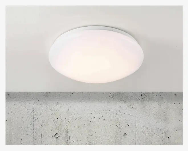 Et rundt, loftmonteret armatur med en glat, hvid, matteret skærm, der spreder lyset jævnt. Designet er minimalistisk og moderne uden synlige skruer eller dekorative elementer, hvilket gør det velegnet til forskellige indretninger. Armaturet sidder tæt på loftet og giver et rent og diskret udtryk.